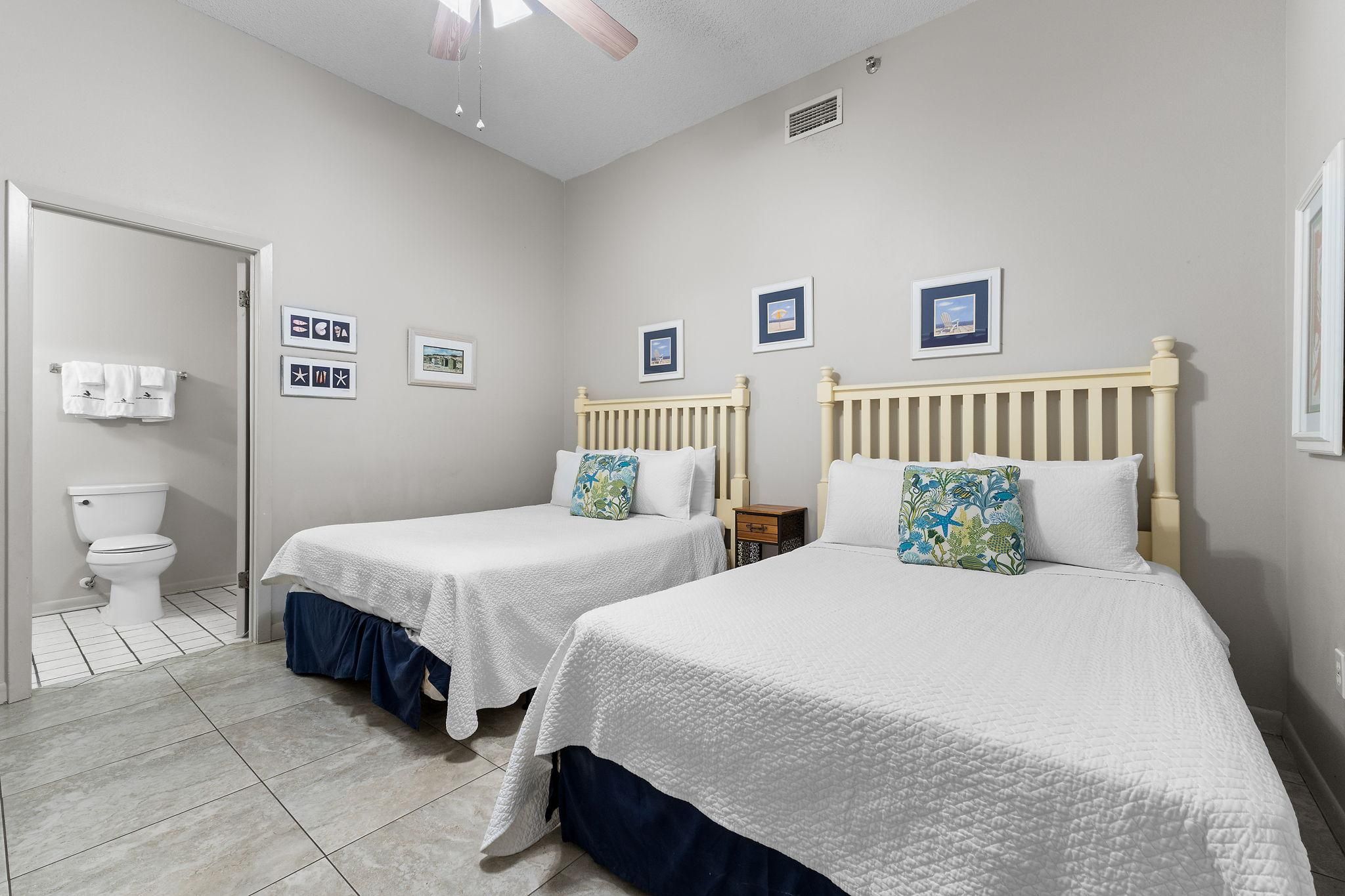 A bedroom with two beds, a toilet, and a shower area.