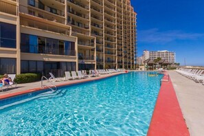 A hotel with a swimming pool, multiple balconies, and a clear blue sky. - Phoenix 5 106 (Orange Beach)