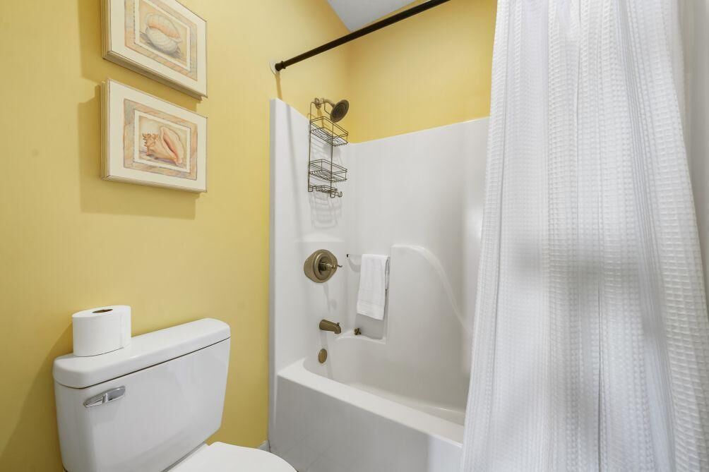Une salle de bain avec des toilettes, une baignoire et deux tableaux encadrés au mur.