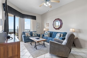 A living room with a sofa, armchair, coffee table, and a ceiling fan. - Phoenix 5 106 (Orange Beach)