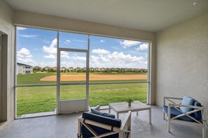 A room with a large window overlooking a baseball field, a small table, and two chairs. - Last Minute Disney Getaway! Luxury Condo with Private Balcony. Book Now! #138341 (Orlando)
