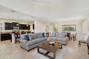 A spacious living area with a gray sectional sofa, a wooden coffee table, and a kitchen in the background. - Paradise Palms Resort 103 (Orlando)
