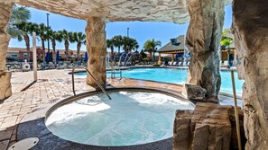 Zona de jacuzzi con piscina, rodeada de palmeras y sillas de descanso.