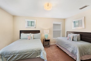 A bedroom with two beds, a nightstand, a lamp, and two wall-mounted picture frames. - Paradise Palms Resort 103 (Orlando)