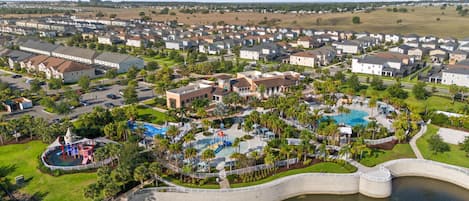 An aerial view of a residential area with houses, a swimming pool, and a park.