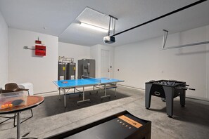 Une pièce équipée d’une table de ping-pong, d’un baby-foot et d’une petite table sur laquelle sont posées des balles de ping-pong.