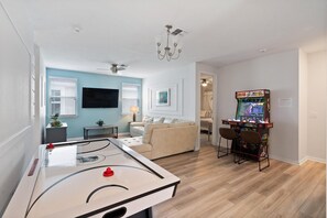 Un salon équipé d’une table de billard, d’un canapé, d’un téléviseur et d’une console de jeux.