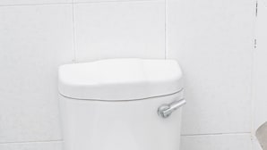 A white toilet with a chrome handle, a visible water pipe, and a white sink with a chrome faucet. - JALITHS Boutique Hotel (Lusaka)