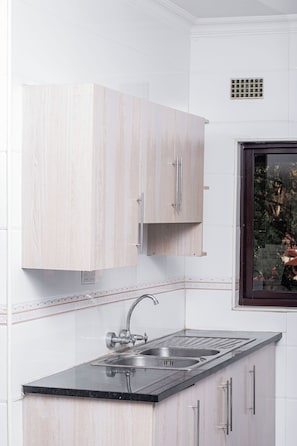 A kitchen with a double sink, stainless steel faucet, and light wood cabinetry.