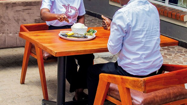 Two people seated at a wooden table with a meal in front of them. - JALITHS Boutique Hotel (Lusaka)