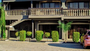 A two-story building with a balcony, a staircase, and a car parked in front. - JALITHS Boutique Hotel (Lusaka)