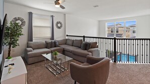 A spacious balcony with a pool, a gray sectional sofa, a glass coffee table, and a ceiling fan. - Storey Lake Resort 545 (Orlando)