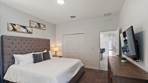A hotel room with a large bed, a dresser, a mirror, and a television. - Storey Lake Resort 545 (Orlando)