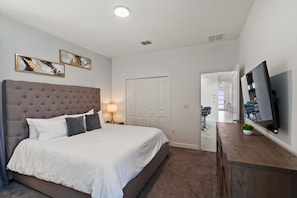 A hotel room with a large bed, a dresser, a mirror, and a television. - Storey Lake Resort 545 (Orlando)