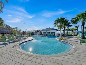 A clear blue pool with a surrounding patio, lounge chairs, and palm trees. - Storey Lake Resort 545 (Orlando)