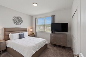 A hotel room with a bed, a TV, a dresser, and a window with blinds. - Storey Lake Resort 545 (Orlando)