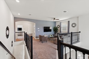 A spacious living area with a television, seating, and a staircase. - Storey Lake Resort 545 (Orlando)