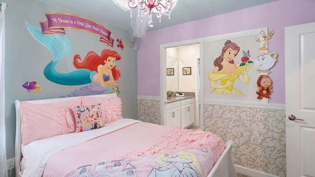 Un dormitorio con cama, cómoda, espejo y adornos en la pared, incluyendo una sirena y una princesa.
