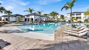 Piscina con sillas de descanso, palmeras y edificios modernos al fondo.
