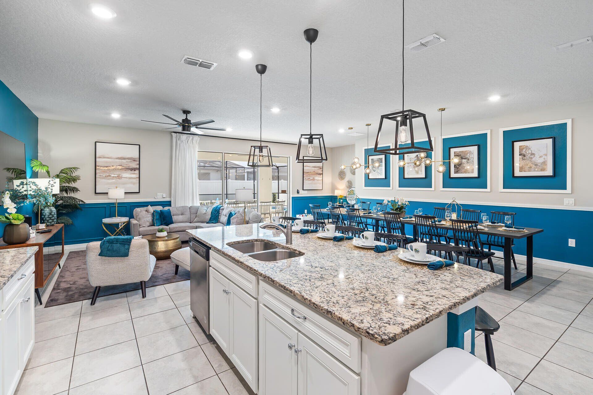 A modern kitchen with granite countertops, a central island, and a dining area with blue chairs.