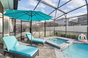 A backyard with a swimming pool, two lounge chairs, a blue umbrella, and a small inflatable pool. - Windsor Island Resort 463 (Orlando)