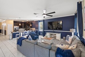 Ein modernes Wohnzimmer mit grauem Sofa, Fernseher und Deckenventilator.