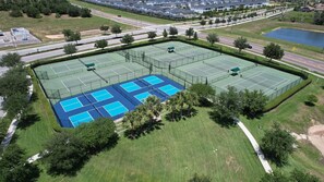 A tennis court complex with multiple courts, surrounded by greenery and residential buildings. - Championsgate 931 - Eight Bedroom Villa, Sleeps 20 (Orlando)