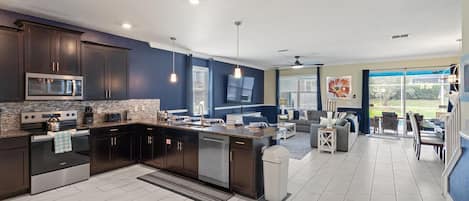 Una cocina moderna con armarios oscuros, una isla central y un comedor con vistas.