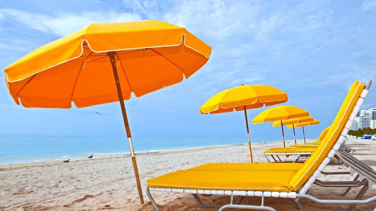 A beach with yellow sun umbrellas and lounge chairs.