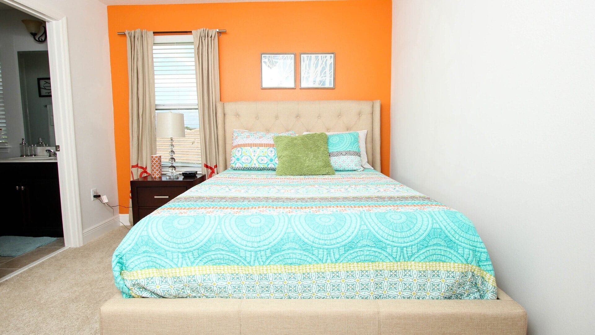 A bedroom with a bed, a nightstand, a lamp, and a window with curtains.