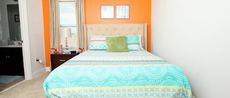 A bedroom with a bed, a nightstand, a lamp, and a window with curtains.