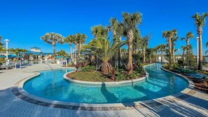 Une piscine à bordures courbes, entourée de palmiers et bordée d’une allée pavée.