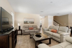 A living room with a flat-screen TV, two sofas, a coffee table, and a painting on the wall. - Championsgate 994 - Six Bedroom Villa, Sleeps 14 (Orlando)