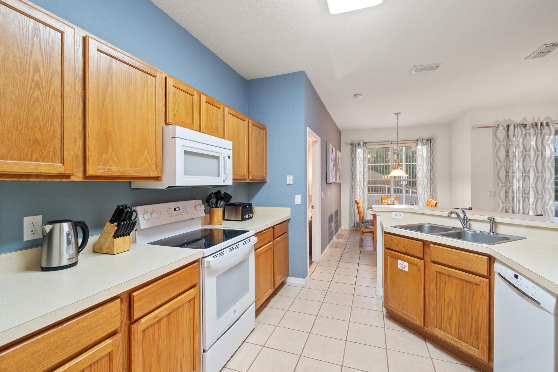 A kitchen with wooden cabinets, a white stove, a microwave, and a sink.