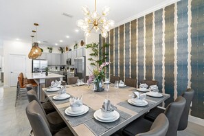Een moderne eetruimte met een lange tafel voor zes personen, omringd door stoelen, en een decoratieve vaas met bloemen.