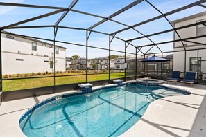 Een zwembad met glazen omheining, omringd door ligbedden en een jacuzzi.