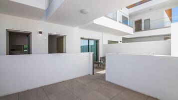 A modern interior with a spacious open-plan layout, a balcony, and a view of the sky.