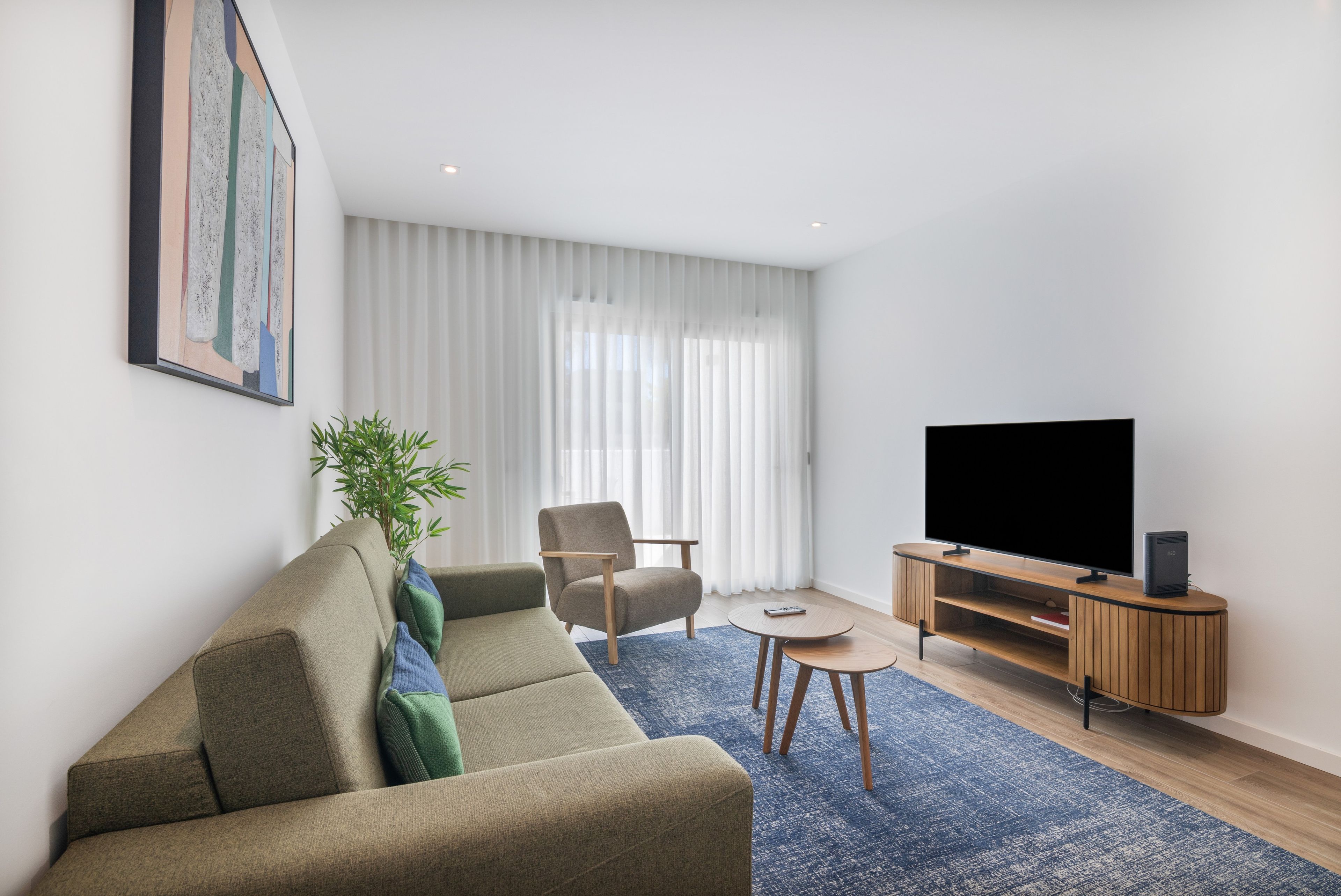A modern living room with a sofa, a chair, a TV, and a small table.