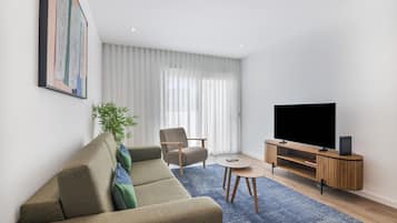 A modern living room with a sofa, a chair, a TV, and a small table.