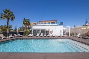 A modern hotel with a swimming pool, lounge chairs, and palm trees. - Apartment Luxury 2br with Terrace  5-min Walk beach front (Tavira)