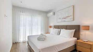 A hotel room with a large bed, a nightstand, a lamp, and a painting on the wall.
