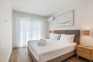 A hotel room with a large bed, a nightstand, a lamp, and a painting on the wall. - Apartment Luxury 2br with Terrace  5-min Walk beach front (Tavira)