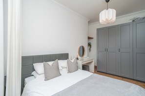 Une chambre à coucher avec un lit, une table de chevet, un miroir et une armoire.
