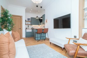 A modern living room with a sofa, a coffee table, and a TV mounted on the wall. - Quiet Beach Retreat | Free Parking - Pass the Keys (Edinburgh)