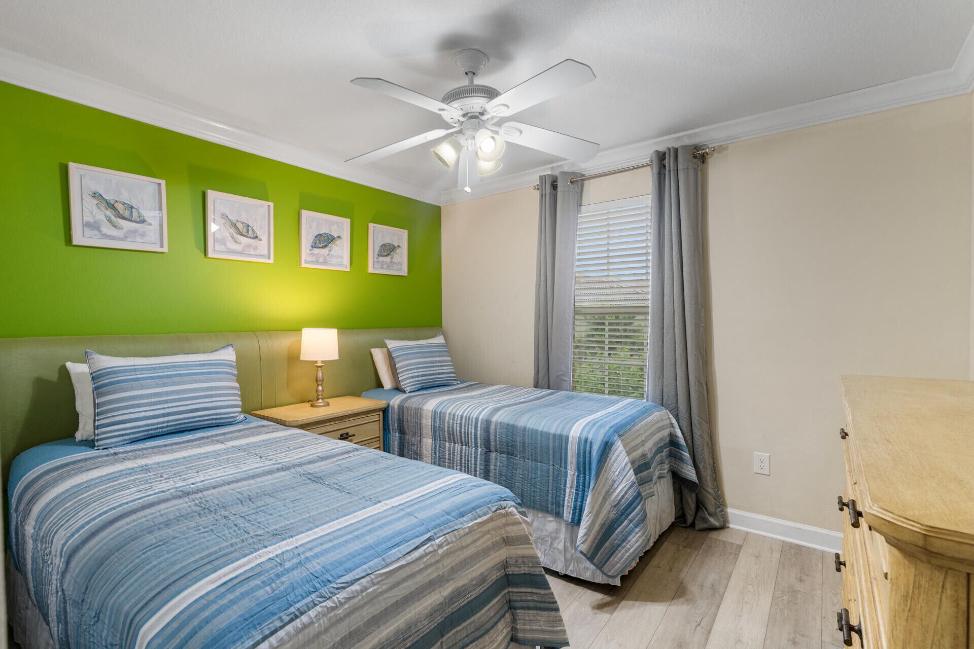A bedroom with two beds, a ceiling fan, and artwork on the wall.