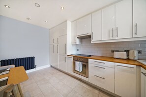 Een moderne keuken met witte kasten, een houten aanrecht, een ingebouwde oven en een broodrooster.