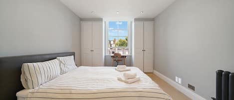 A bedroom with a bed, a chair, and a view of the outside.