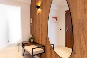 Ein modernes Zimmer mit einer Wandpaneele aus Holz, einem runden Spiegel, einem kleinen Tisch mit Kissen und einer Tür mit einem Hinweisschild.
