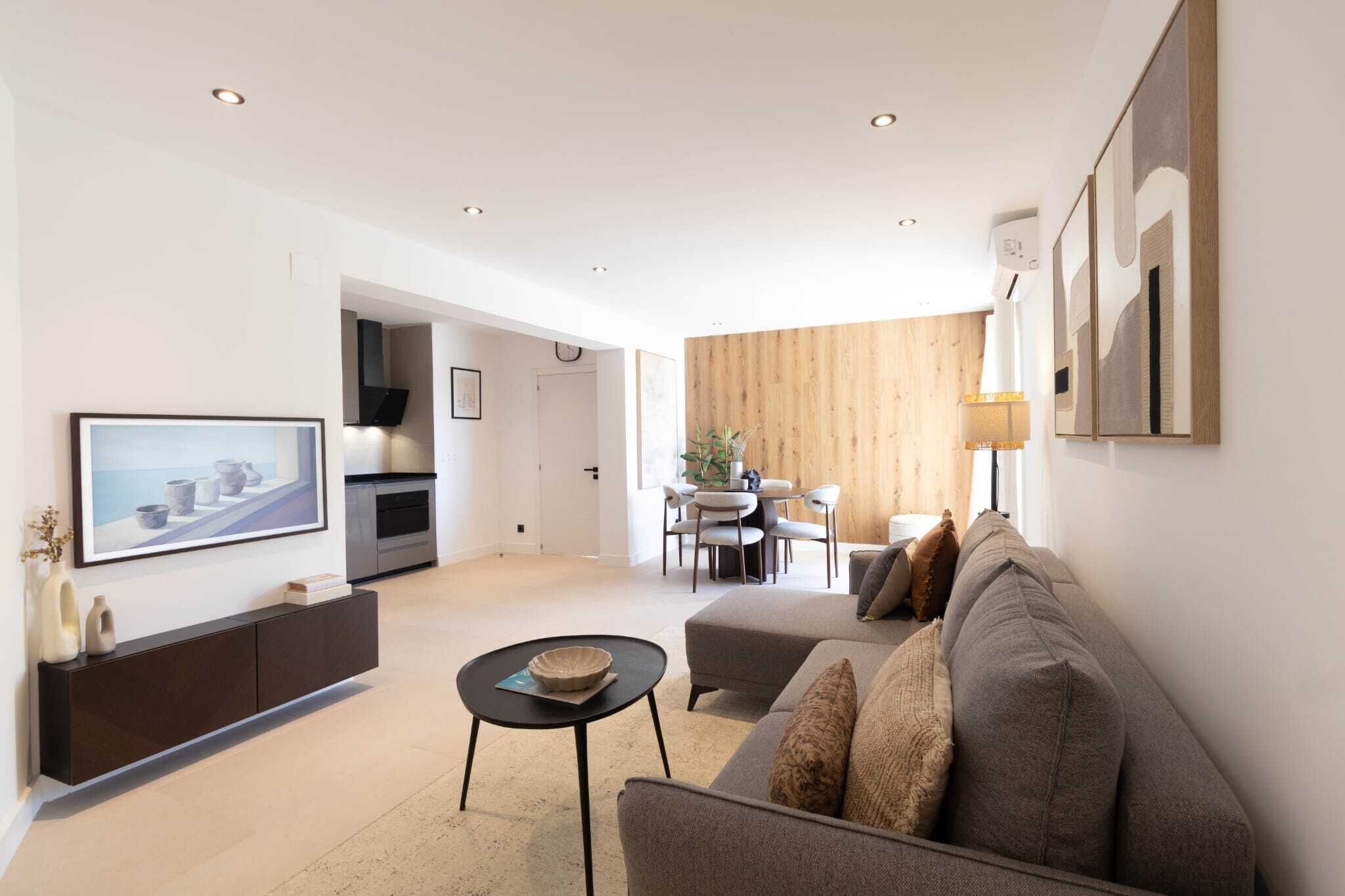 A modern living room with a sofa, coffee table, and a dining area with chairs.