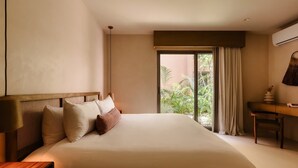 A hotel room with a large bed, a desk, and a view of greenery outside. - Aflora Moon 3 bd First FloorBeach Club + Breakfast (Tulum)